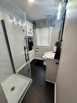 Ein Badezimmer mit Glasdusche, Waschbecken in Weiß und Toilette.