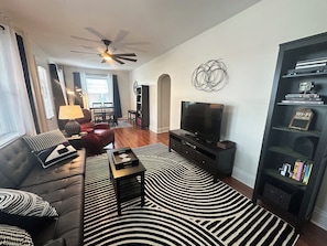 A living room with a sofa, a coffee table, a television, and a bookshelf.