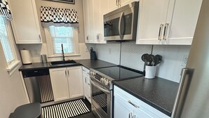 A modern kitchen with white cabinets, a stainless steel refrigerator, a microwave, and a dishwasher.