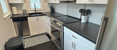 A modern kitchen with white cabinets, a stainless steel refrigerator, a microwave, and a dishwasher.