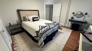 A bedroom with a bed, a desk, and a chair.