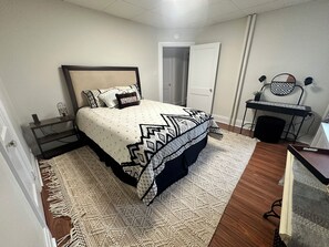 A bedroom with a bed, a desk, and a chair.