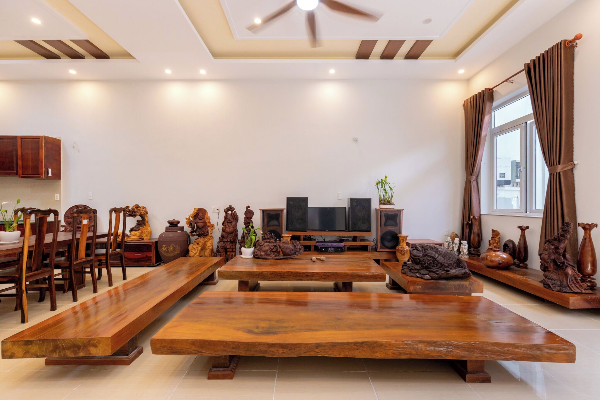 Een ruime woonkamer met een grote houten eettafel, meerdere stoelen, een televisie en decoratieve objecten.