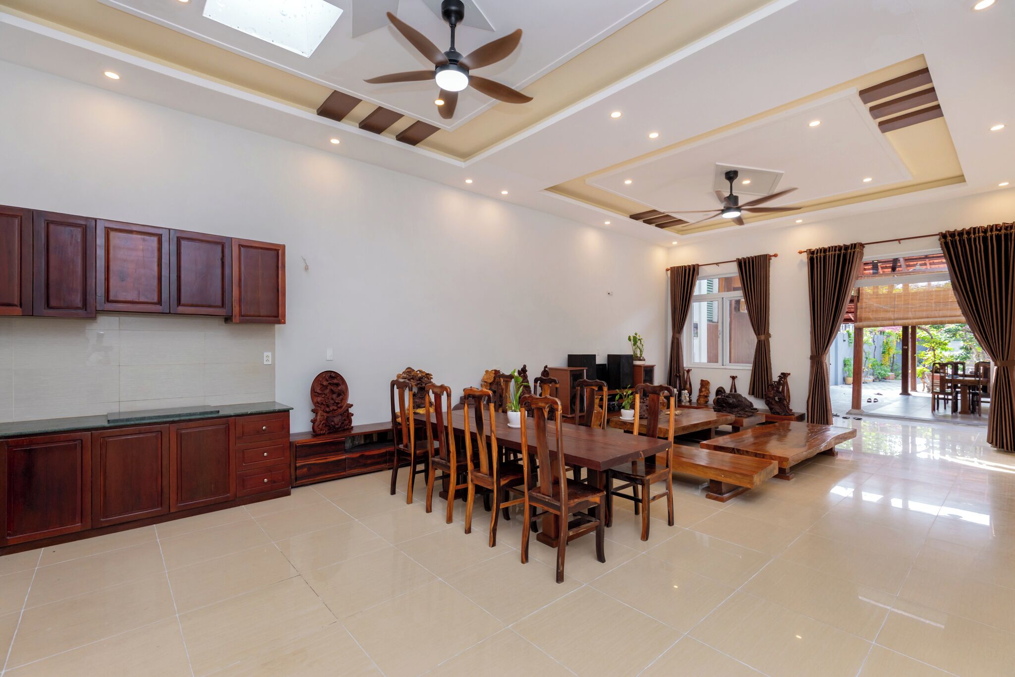 A spacious dining area with wooden furniture and ceiling fans.