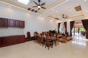 A spacious dining area with wooden furniture and ceiling fans.