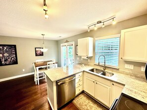 A kitchen with white cabinets, a stainless steel dishwasher, a granite countertop, and a window with blinds. - Relaxing Fletcher Townhome with proximity to Asheville and Hendersonville (Fletcher)