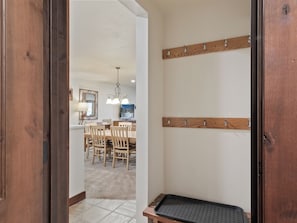 A wooden door leading to a dining area with a chandelier, a coat rack, and a television on the wall. - Snow Flower 56 | Ski-In/Out | Pool | Hot Tub | Parking | Tennis | Pickleball | Park City (Park City)