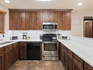 A kitchen with wooden cabinets, stainless steel appliances, and a tiled backsplash. - Snow Flower 56 | Ski-In/Out | Pool | Hot Tub | Parking | Tennis | Pickleball | Park City (Park City)