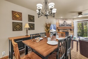 A dining area with a wooden table, chairs, a chandelier, and artwork on the walls.