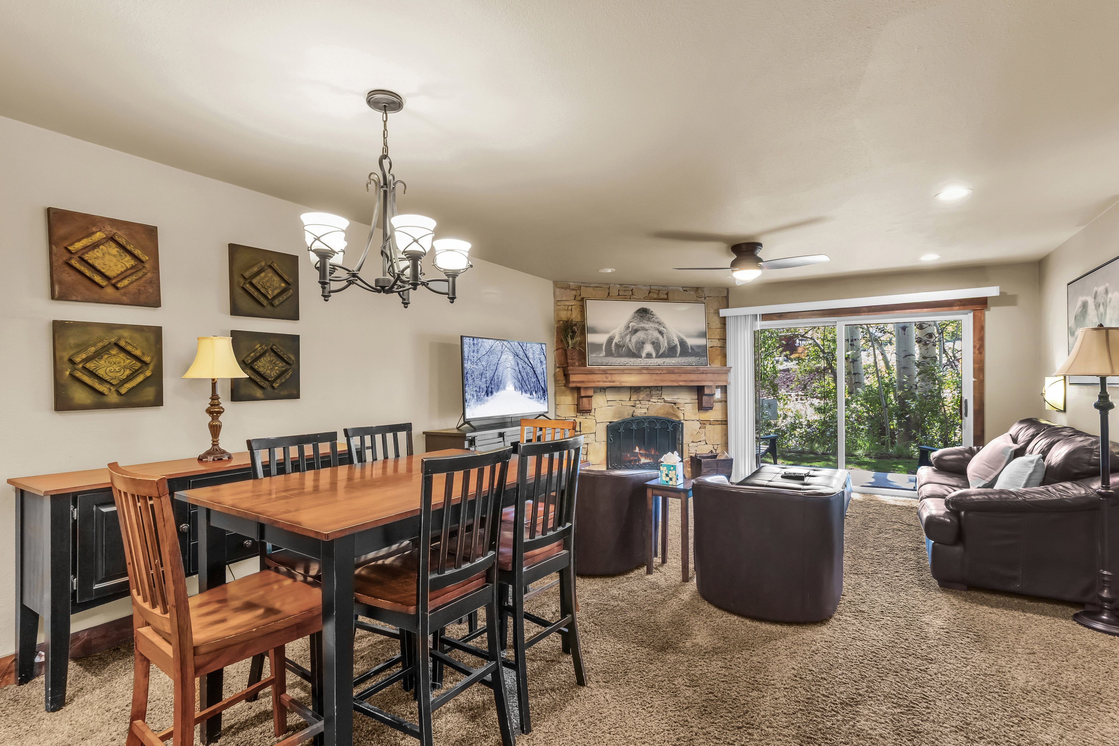 A dining area with a wooden table and chairs, a fireplace, and a television.