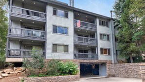 En byggnad med flera våningar, balkonger, en garageuppfart och en mur av sten som används som stödmur.