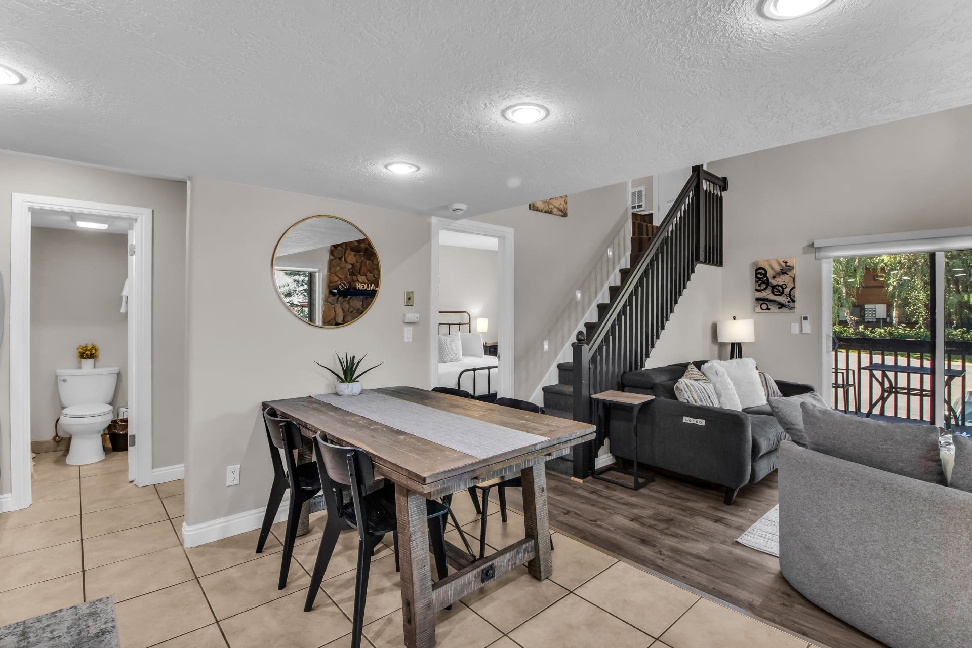 Ein modernes Wohnzimmer mit Esstisch, Sofa und Treppe.