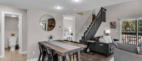 Ein modernes Wohnzimmer mit Esstisch, Sofa und Treppe.
