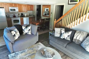 Ein Wohnzimmer mit zwei Sofas, einem Couchtisch und einer Küche im Hintergrund.