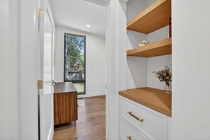 Een modern interieur met een houten vloer, witte wanden en inbouwplanken met decoratieve objecten.