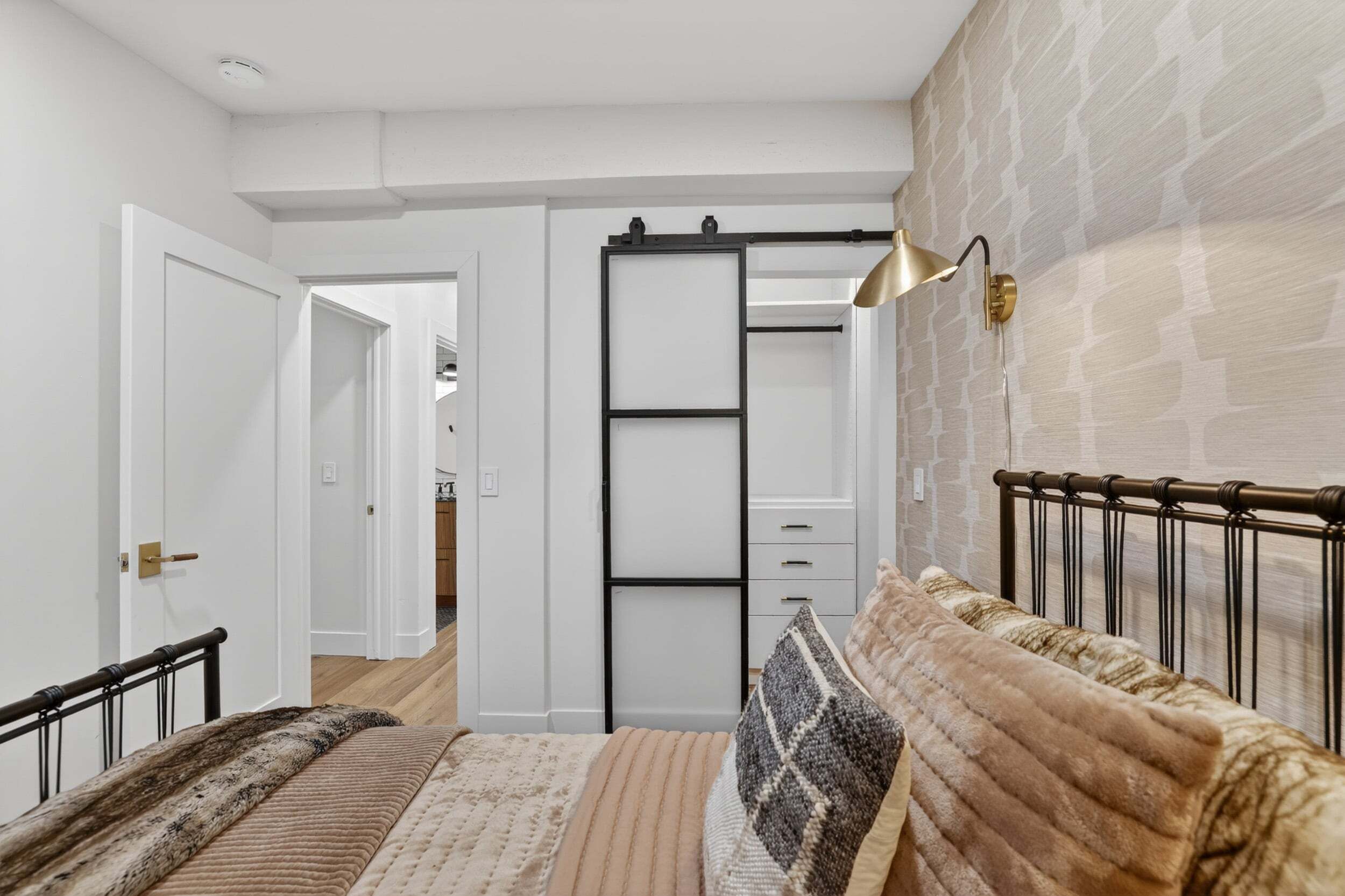 A bedroom with a bed, a wardrobe, and a hanging light fixture.