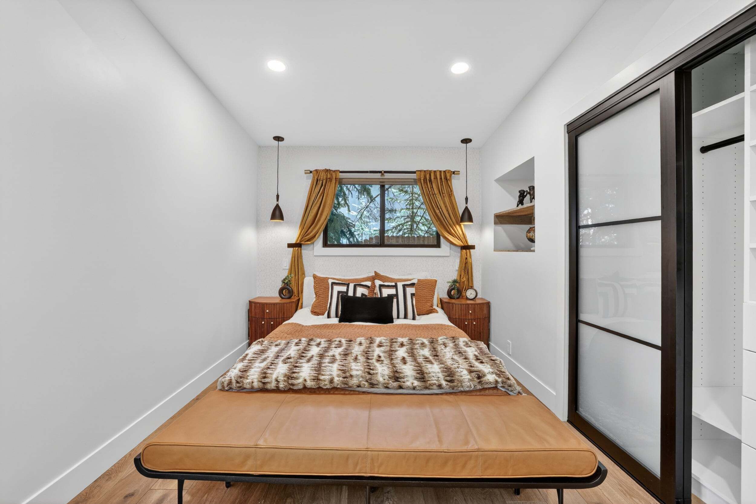 Une chambre à coucher avec un lit, une fenêtre avec des rideaux, des tables de chevet et une armoire.