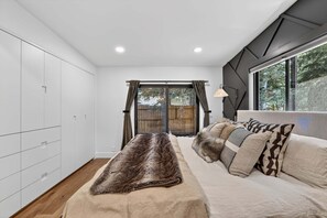 A modern bedroom with a bed, a wardrobe, and a large window. - Hulen Hideaway | Hot Tub | Perfect Location (Ketchum)