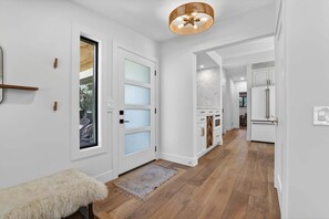 A modern kitchen with white cabinetry and a wooden floor. - Hulen Hideaway | Hot Tub | Perfect Location (Ketchum)