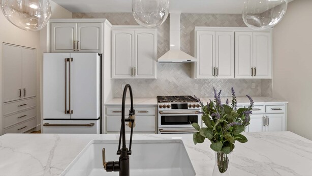 A modern kitchen with white cabinetry, a built-in oven, and a marble countertop. - Hulen Hideaway | Hot Tub | Perfect Location (Ketchum)