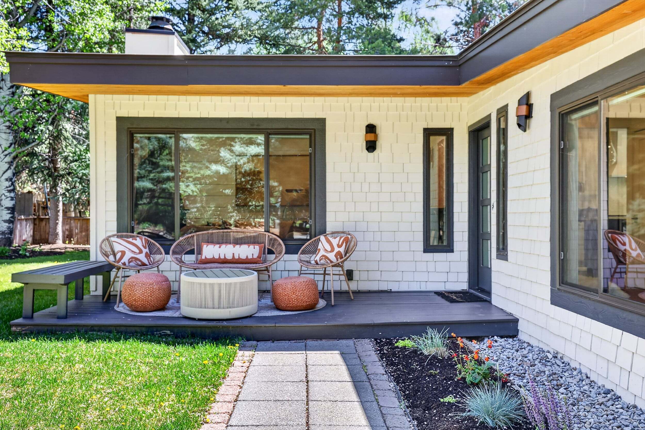 A modern house with a patio, outdoor seating, and a garden.