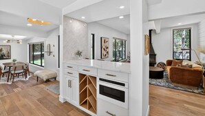 A modern kitchen with white cabinetry, a herringbone-patterned backsplash, and a built-in oven. - Hulen Hideaway | Hot Tub | Perfect Location (Ketchum)