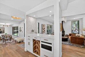 A modern kitchen with white cabinetry, a herringbone-patterned backsplash, and a built-in oven. - Hulen Hideaway | Hot Tub | Perfect Location (Ketchum)
