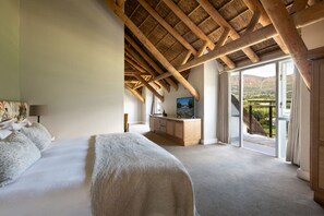 Ein Schlafzimmer mit einem großen Bett, einem Schreibtisch mit Computer und einem Balkon mit Blick.
