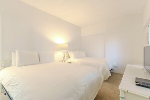 A hotel room with two beds, a bedside table, a lamp, a television, and a remote control. - Two Bedroom Siesta Beach Condo with a view (Sarasota)