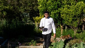 A chef walking in a garden with a metal bowl, surrounded by greenery and a wooden fence. - Mont Rochelle – A Luxurious Escape in Franschhoek, 1028 (Western Cape)