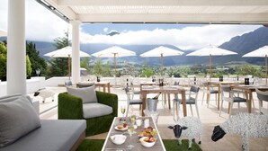 An outdoor dining area with tables and chairs, umbrellas, and a scenic mountain view. - Mont Rochelle – A Luxurious Escape in Franschhoek, 1028 (Western Cape)