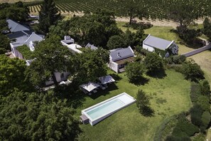 Ein Wohngebiet mit mehreren Häusern, einem Schwimmbad und einem Weinberg im Hintergrund.