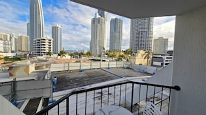 Varanda com vista para edifícios altos, um hotel relógio e palmeiras.