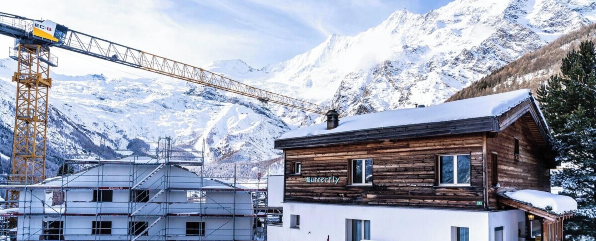 A wooden building with a sign 'Butterfly' in a snowy mountainous area.