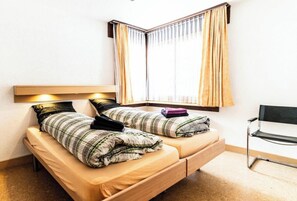 A single bed with a headboard, a window with curtains, and a chair. - Experience Alpine Charm, Wallis 1208 (Valais)