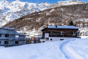 A wooden building with a sign 'Butterfly' in a snowy mountainous area with a ski lift in the background. - Experience Alpine Charm, Wallis 1208 (Valais)
