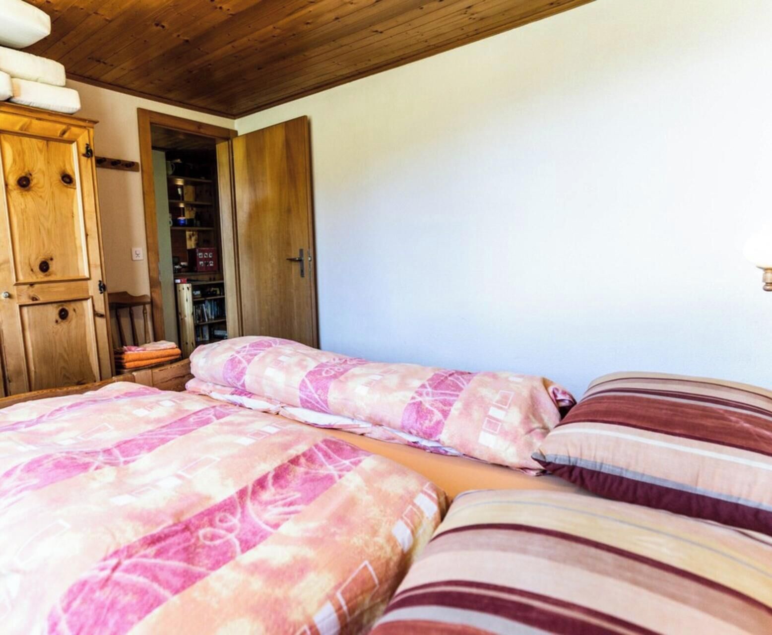 Un dormitorio con dos camas, un armario de madera y una estantería con libros.