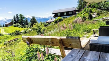 Un banc et une table en bois dans un jardin offrant une vue sur la montagne.