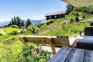 Eine Holzbank und ein Tisch in einem Garten mit Blick auf die Berge.