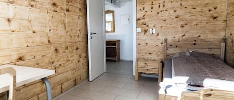 Una habitación con paredes de madera, una cama, un escritorio y una silla.