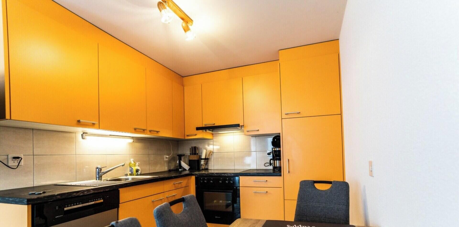 Une cuisine de taille réduite, avec des meubles de rangement en bois, une cuisinière noire et un évier.