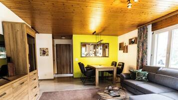 Un salon chaleureux avec un coin repas, un plafond en bois et une grande fenêtre.