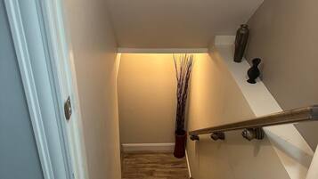 A staircase with a handrail, a vase, and a plant on the landing.