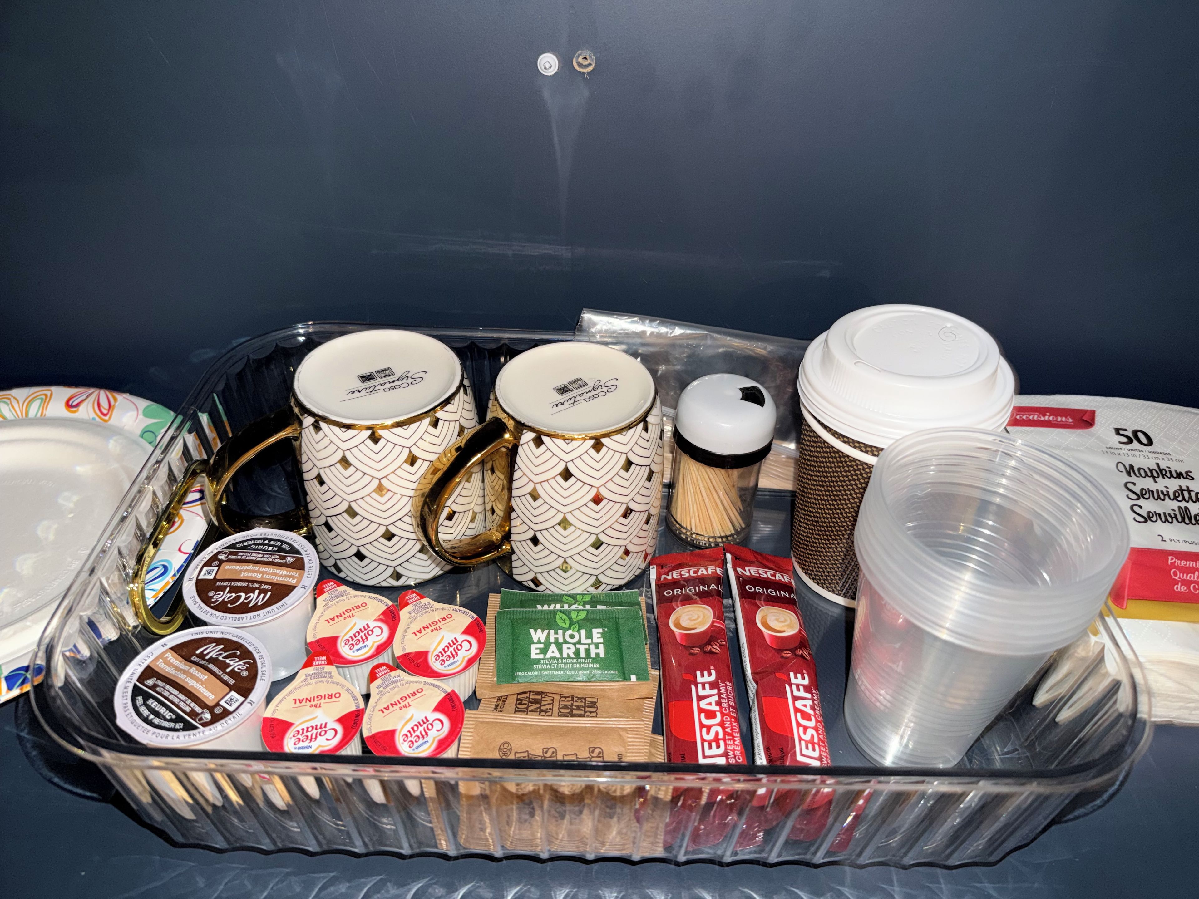 A tray with various items including coffee mugs, coffee cups, and coffee pods.