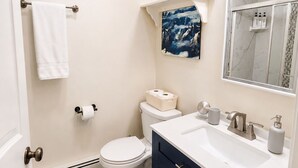 A bathroom with a toilet, sink, and shower area.