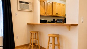 A kitchen with wooden cabinets, a built-in shelf, and two wooden stools.