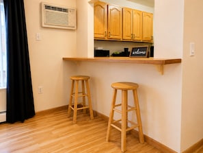 A kitchen with wooden cabinets, a built-in shelf, and two wooden stools.