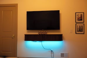 Un téléviseur fixé au mur, avec une étagère en dessous.
