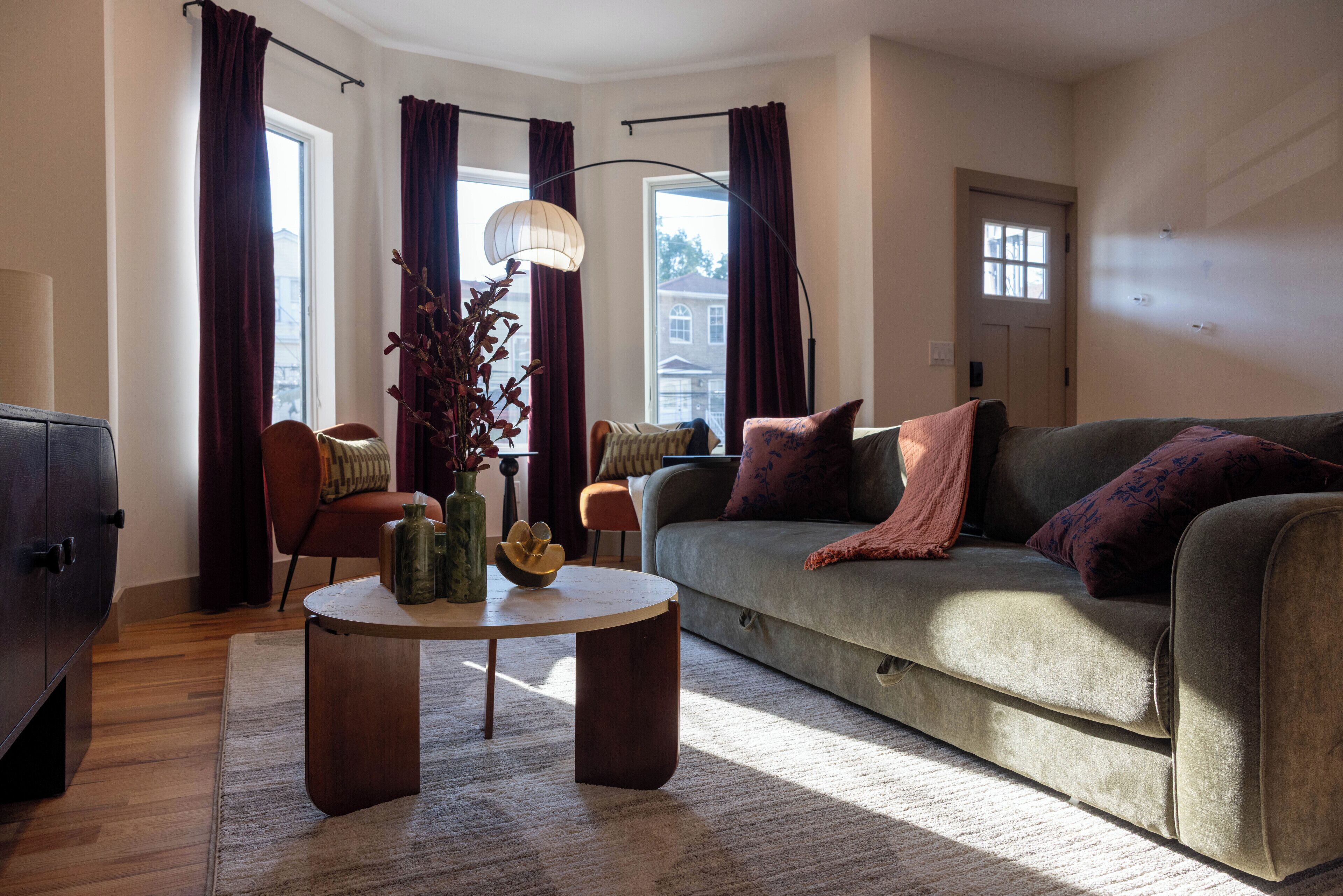 En moderne stue med sofa, lænestole, sofabord og en dekorativ vase.