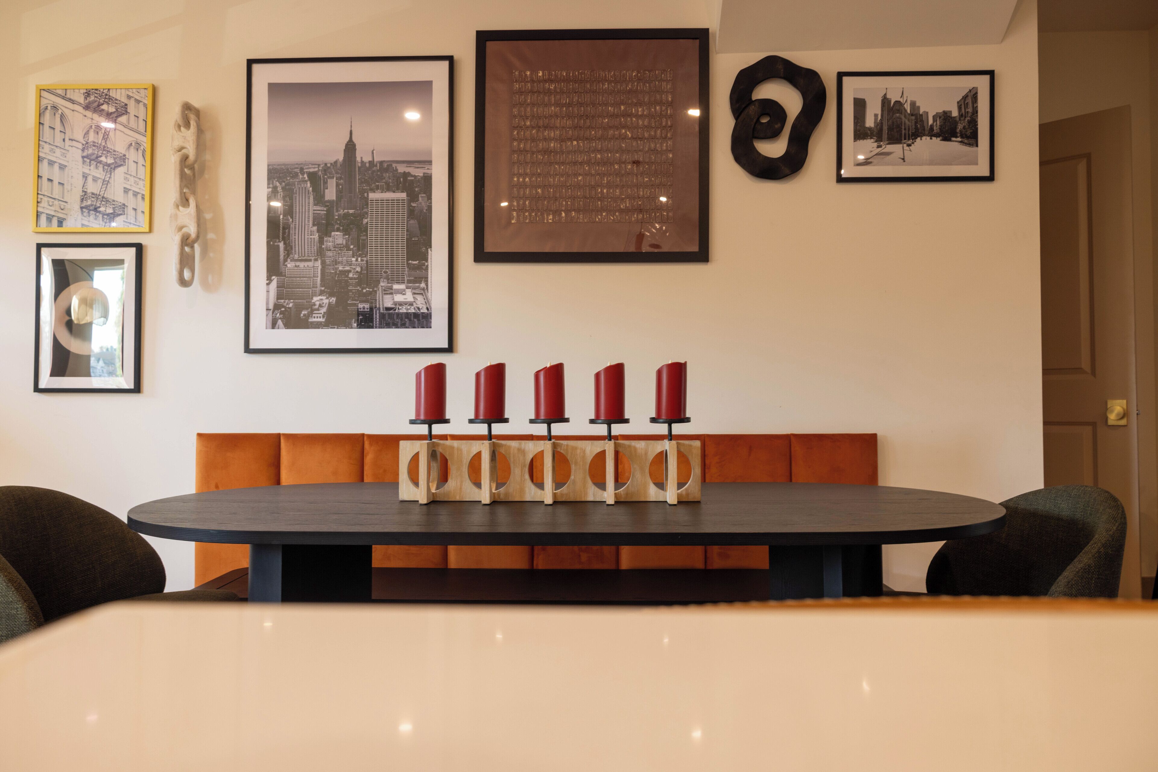 Un coin repas avec une table ronde, un banc en bois et quatre bougies rouges.